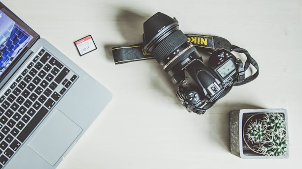 black nikon dslr camera beside silver macbook