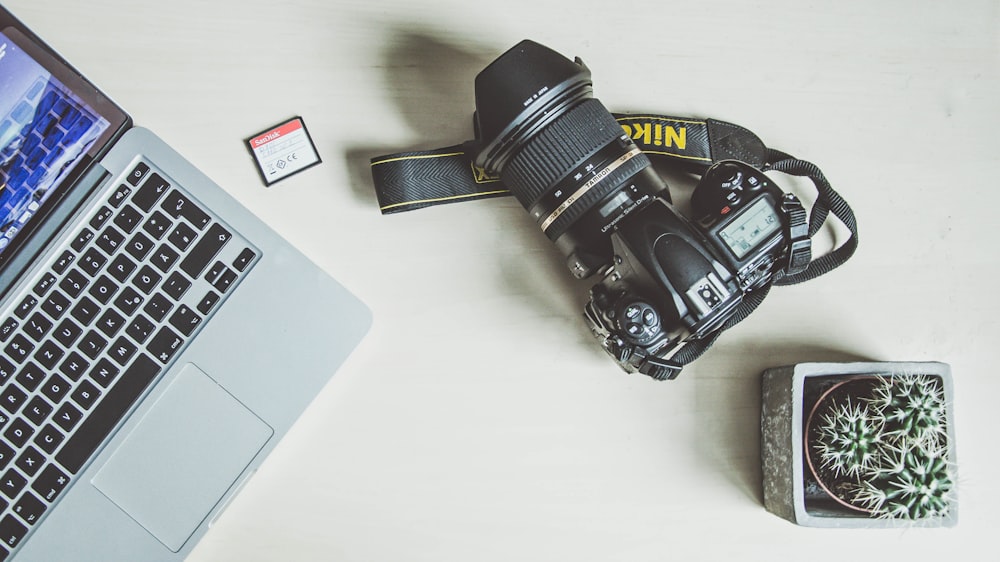 Appareil photo reflex numérique Nikon noir à côté du MacBook argenté