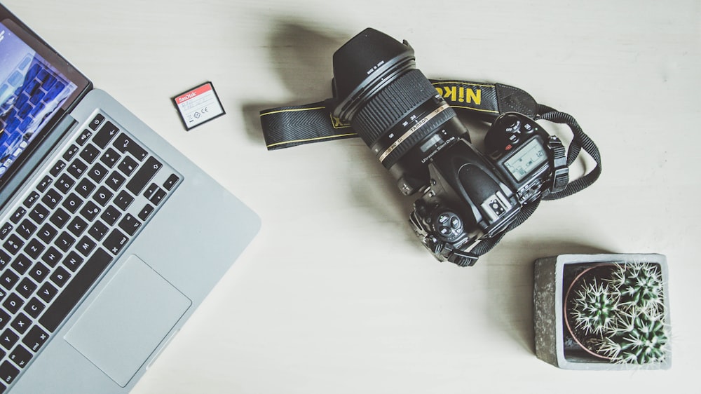 black nikon dslr camera beside silver macbook