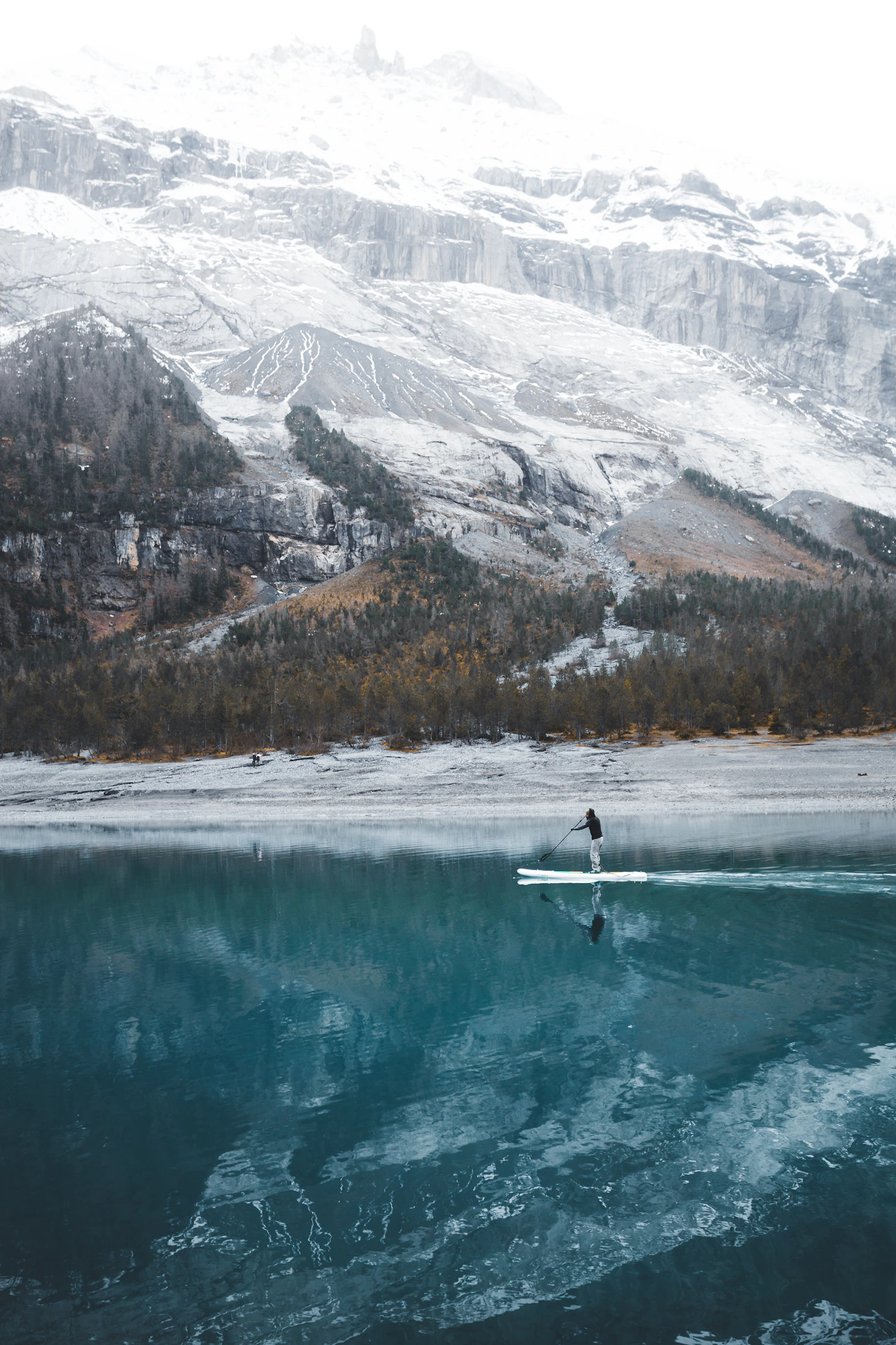 Paddle boarder crossing a mountain lake