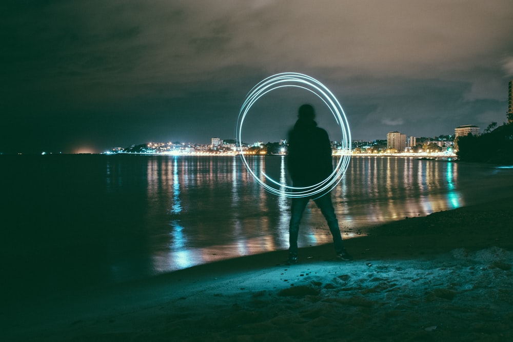 time-lapse photography of man playing with steel wool near seashore