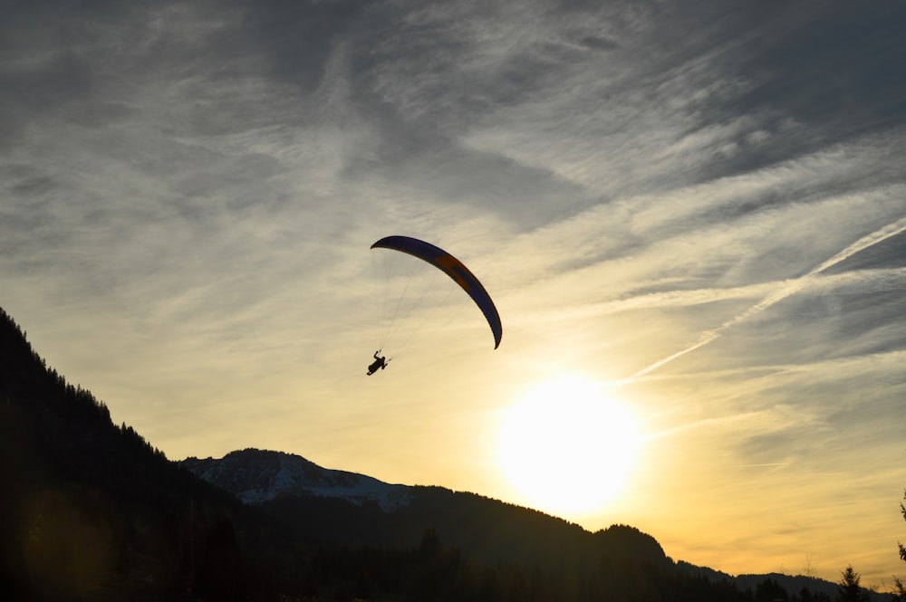 Silueta de la persona que se lanza en paracaídas durante la salida del sol