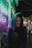 A happy customer wearing a Skyemuse hoodie, smiling outdoors with city lights behind.