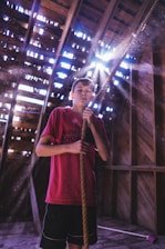 An instructor guiding a young student on the trapeze with sunlight streaming through the studio windows.