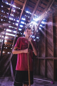 An instructor guiding a young student on the trapeze with sunlight streaming through the studio windows.