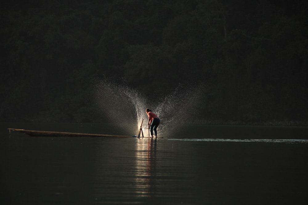 Person, die auf dem Boot steht und Wasser spielt