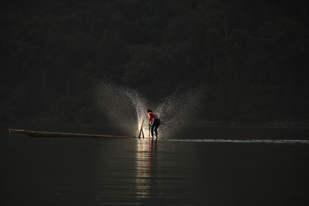 person standing on boat playing water