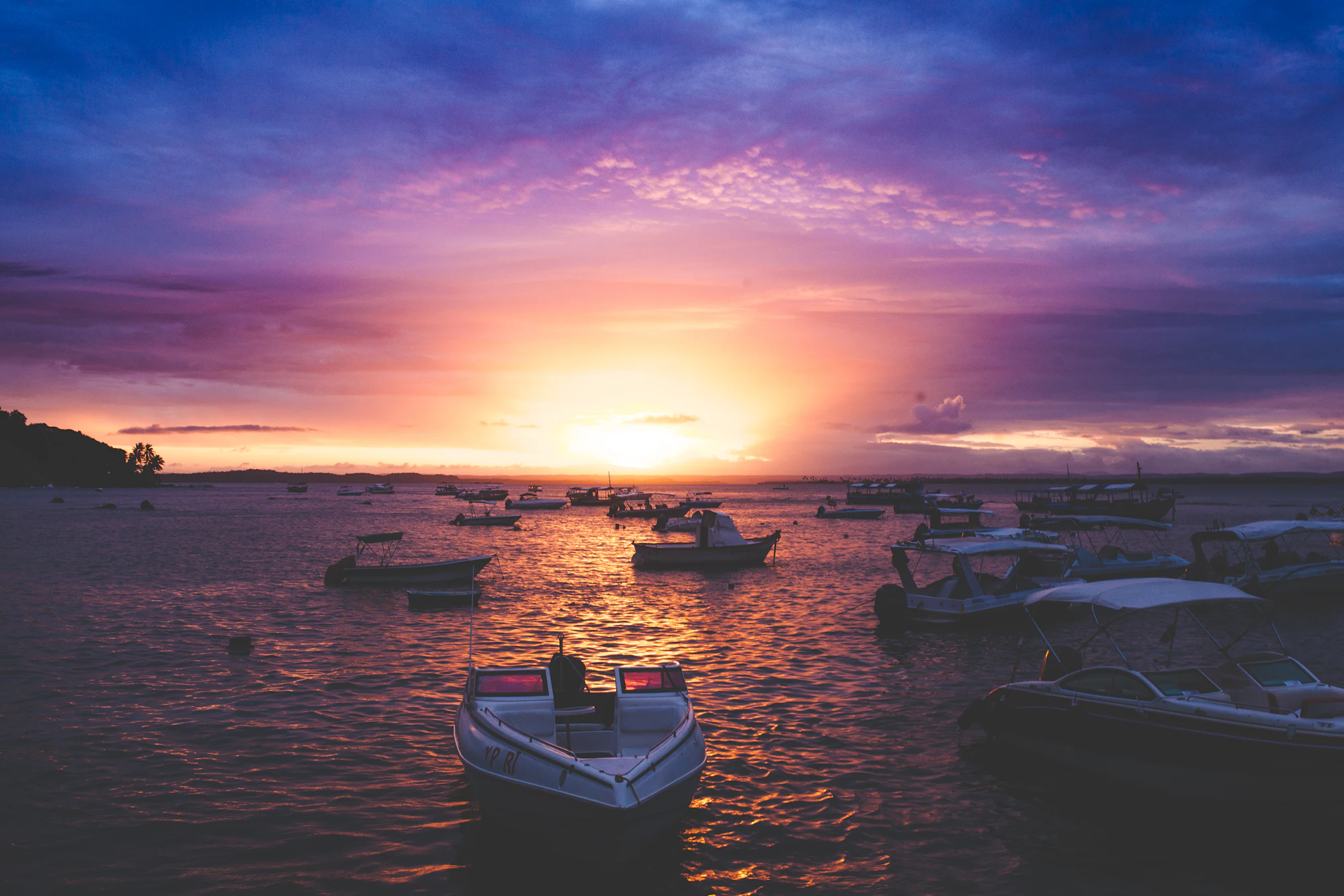 Barcos no mar ao pôr do sol com céu alaranjado