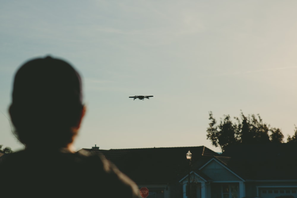 Mann, der tagsüber steht, während er das Flugzeug am Himmel beobachtet