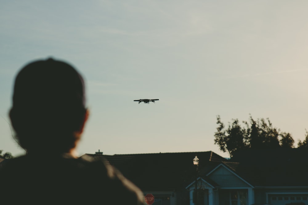 man standing while watching plane on sky during daytime