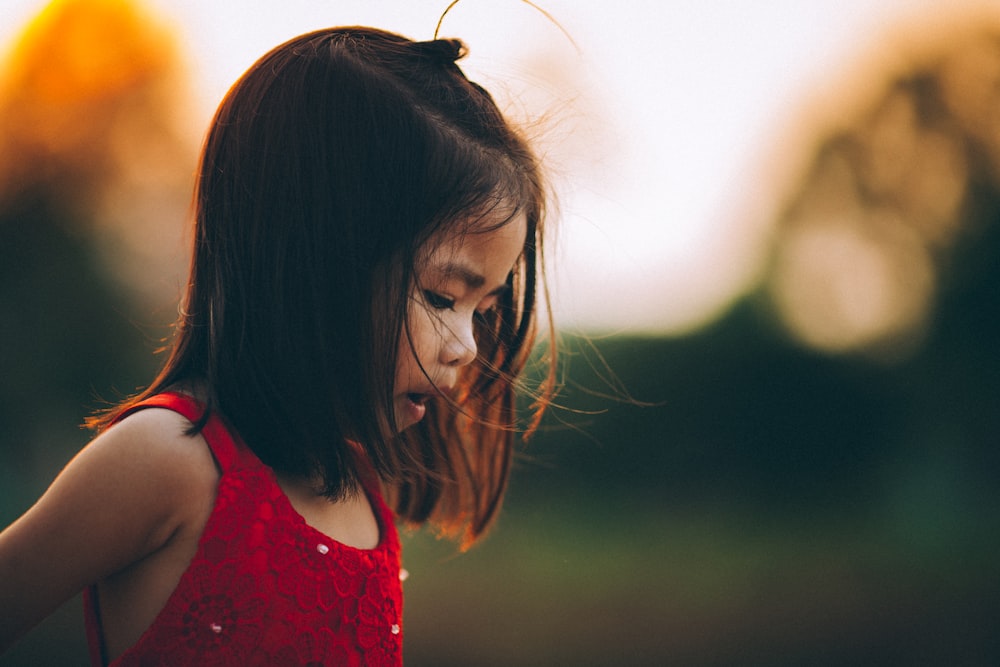 selective focus photography of toddler wearing red tank top