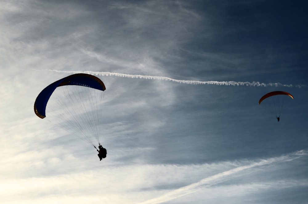 two people riding parachute on clouds during daytime
