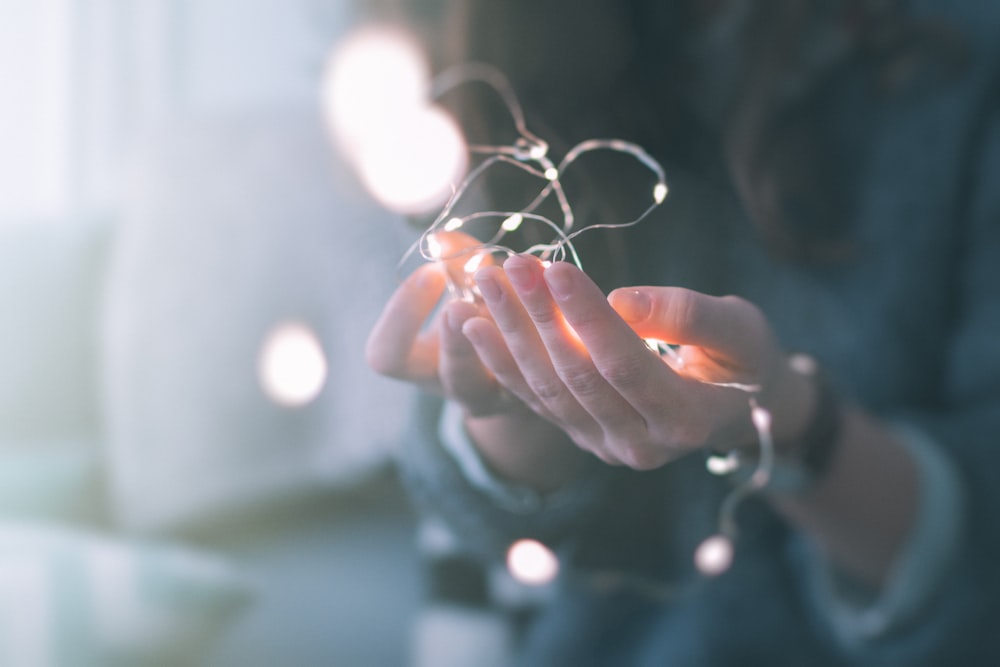 shallow focus photograph of person holding string lights