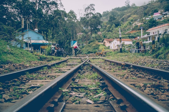 two person riding motorcycle crossing on railroad during daytime in Ooty India