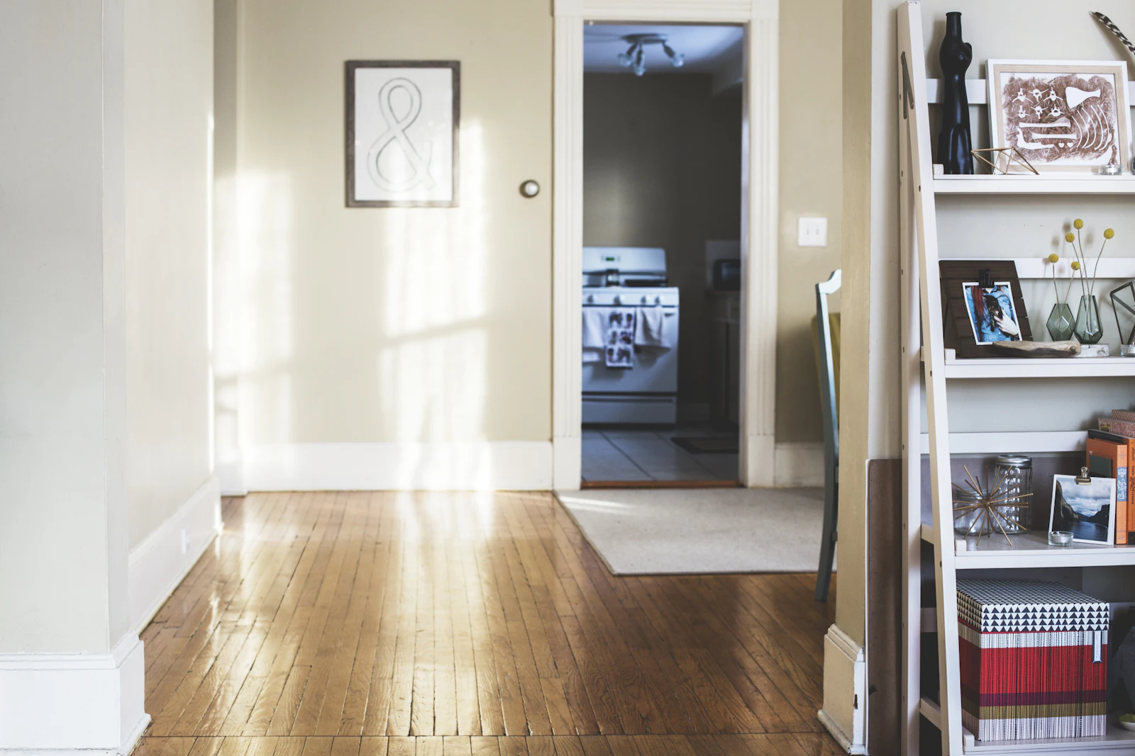 Entrée lumineuse avec parquet, étagère décorative et vue vers la cuisine