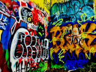 Graffiti artists painting a large wall, their vibrant colors telling stories of the streets.