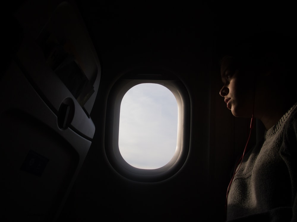 woman using red in-ear headphones while riding airplane