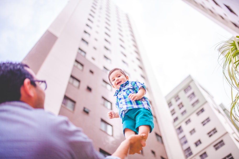 Fotografia de foco raso do pai segurando seu filho na mão direita