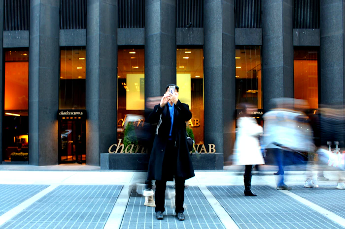 A pedestrian checking a phone while walking quickly along a busy city pavement