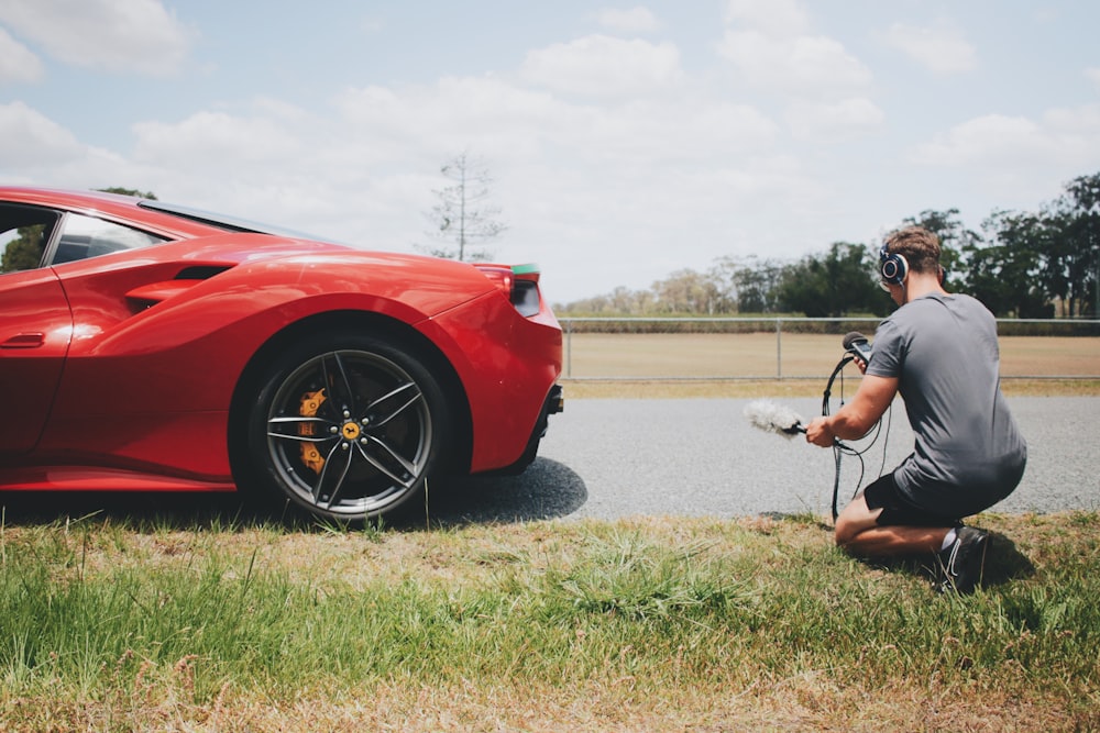 man behind car holding microphone measuring sound