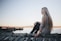 woman sitting on gray dock near bpdy of water