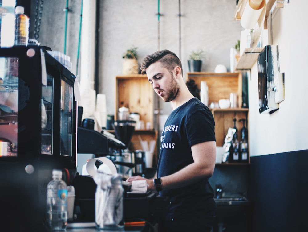 Photographie à mise au point peu profonde d’un homme utilisant une caisse enregistreuse à l’intérieur de la zone du comptoir