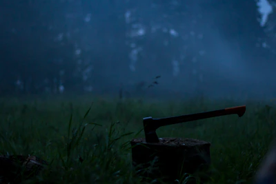 Close-up of a hand gripping an axe ready to throw in a moody, dark environment.