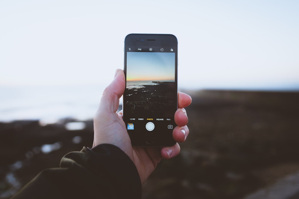 person taking photo of landscapes using iPhone during daytime