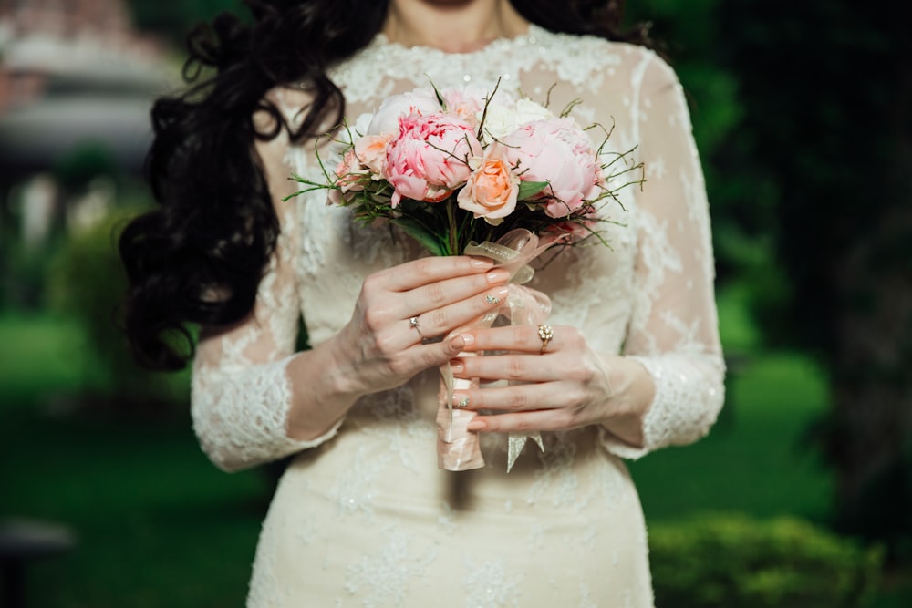 Frau trägt langärmeliges Brautkleid aus weißer Spitze