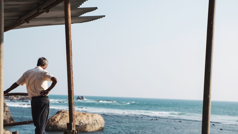 man leaning on fence while facing body of water