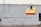 A gray concrete wall with several electrical boxes and conduits. A colorful sign hangs on the wall with a vinyl record graphic and the text 'Tower District Records' along with the words 'Buy Sell Trade Listen' in red. There is a small, partially visible door on the right side.