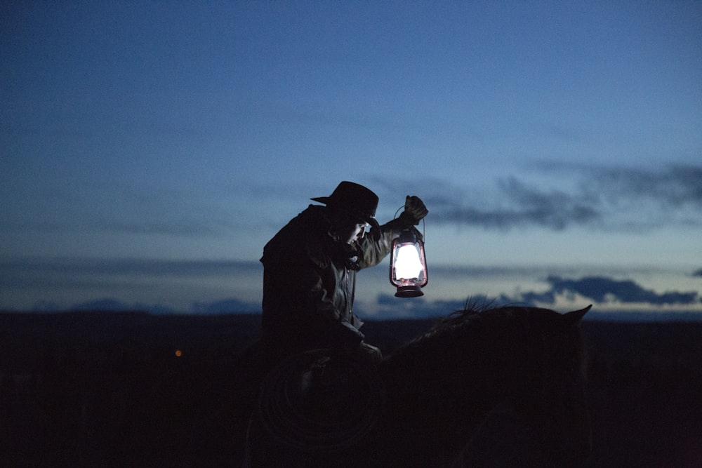 cowboy a cavallo che tiene una lampada