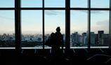 Portrait of a confident agent standing by a window overlooking the city skyline.