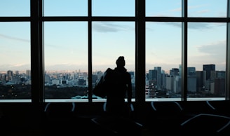 Silhouetted executive in a shadowy boardroom with dramatic lighting and a backdrop of glass skyscrapers.