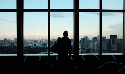 Portrait of a confident agent standing by a window overlooking the city skyline.