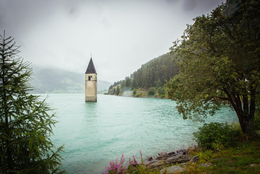 concrete tower surrounded by water near land with trees