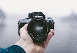 person holding Nikon DSLR camera