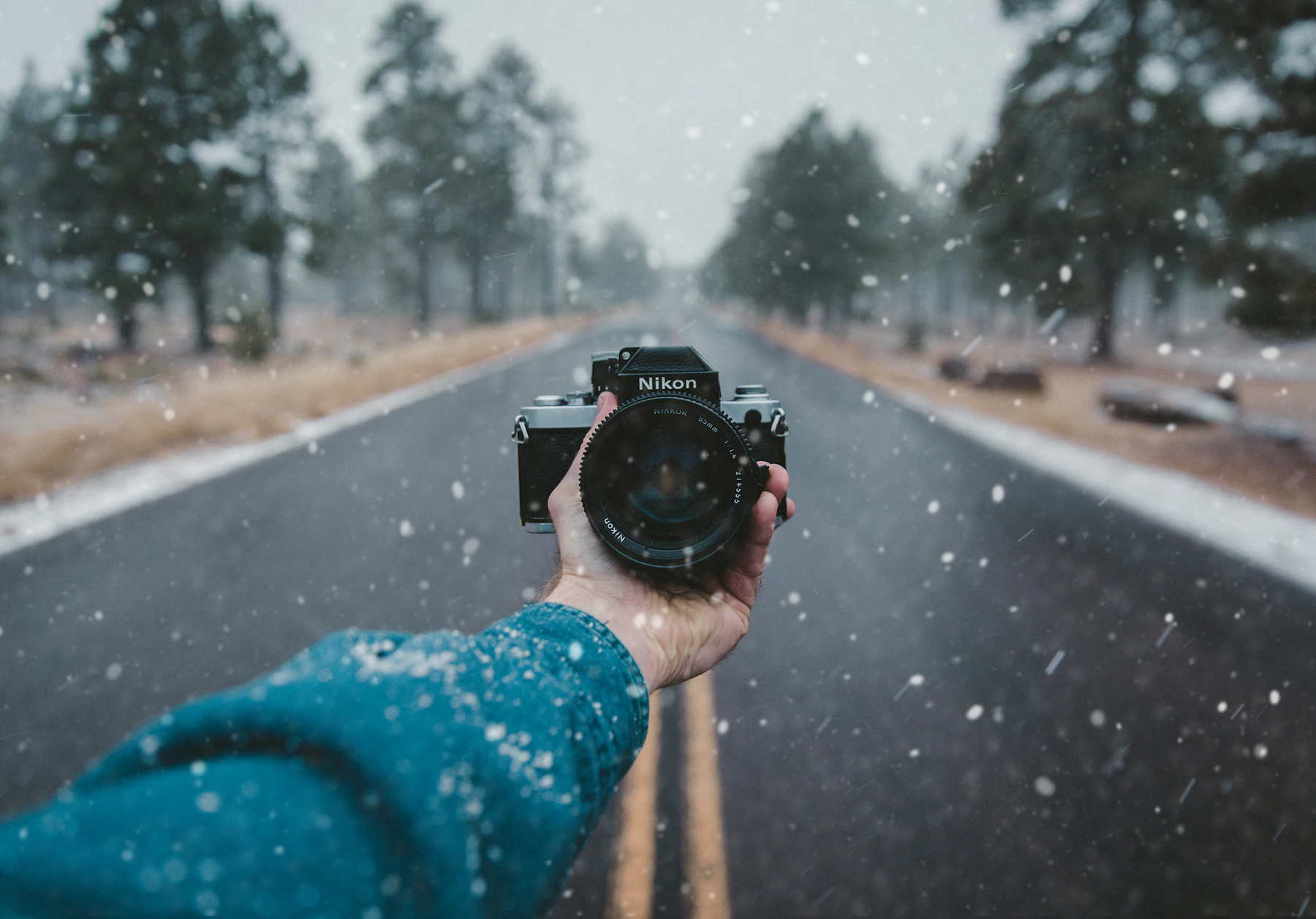 Hand holding Nikon camera on a travel route during a creator shooting scene