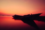 Sunset view with a silhouette of a boat gently floating on the water.