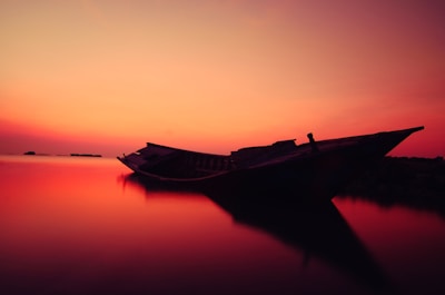 Sunset view with a silhouette of a boat gently floating on the water.