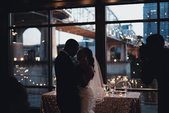 Stylish couple sharing a joyful dance in a sleek urban venue with city lights twinkling behind.