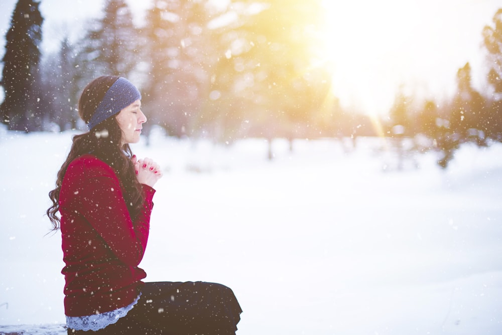 mulher sentada com os olhos fechados cercada pela neve