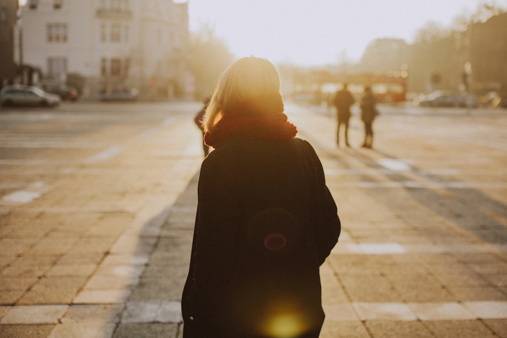 Fotografia da silhueta da mulher com a jaqueta preta na estrada