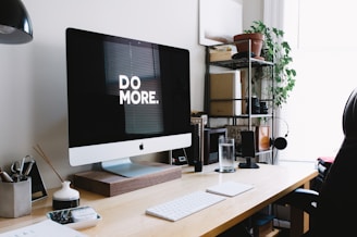 silver iMac with keyboard and trackpad inside room encouraging a message of "Do More"