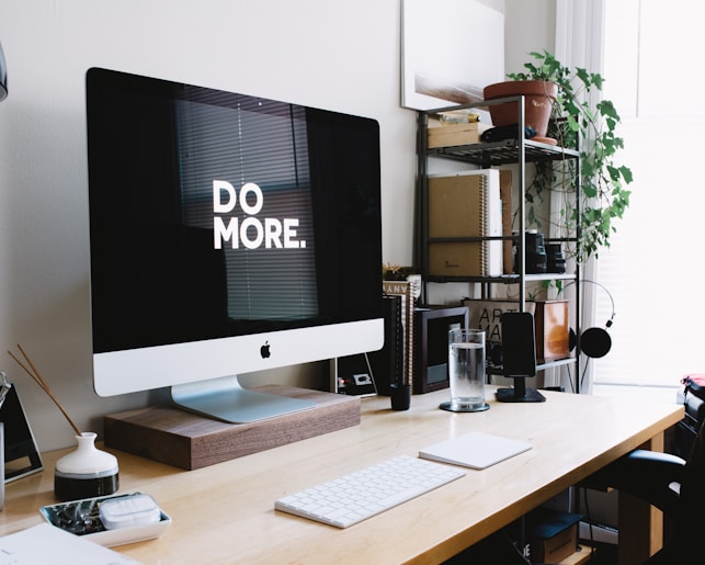 silver iMac with keyboard and trackpad inside room encouraging a message of "Do More"