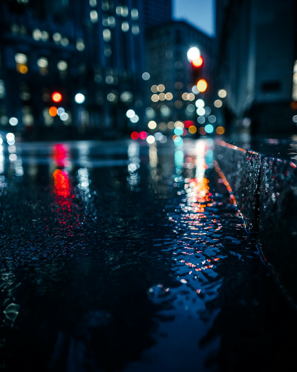 A blurred shot of a wet city street with lights reflecting from vehicles.