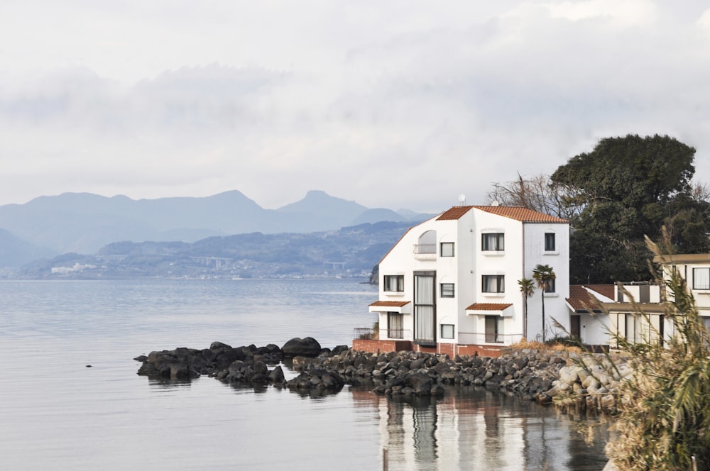 white and brown house at lakeside under grey cloudy sky