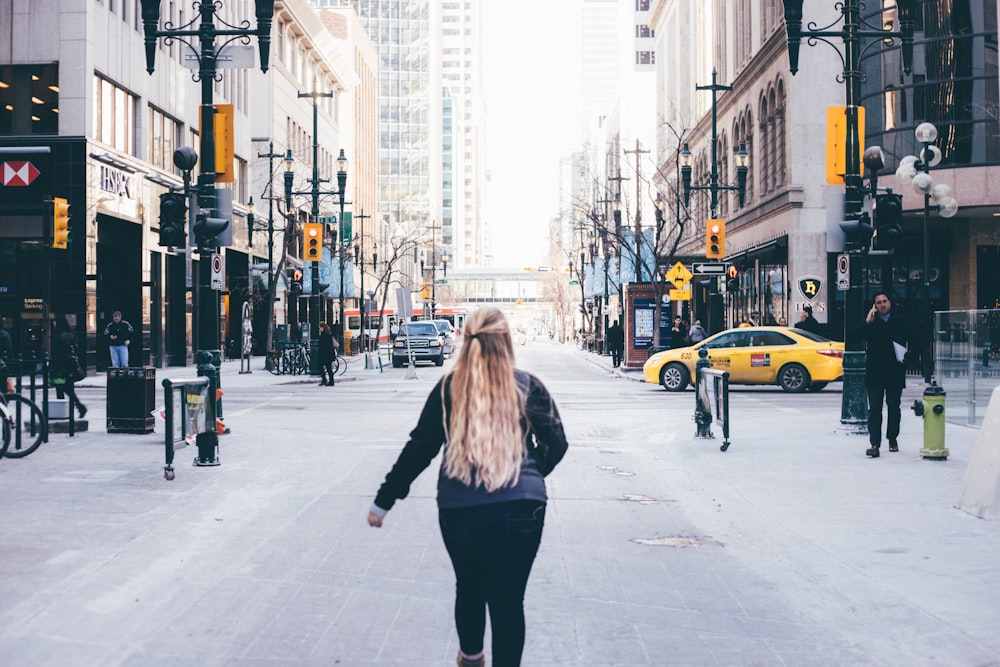 woman in grey and black shirt walking in the middle of street