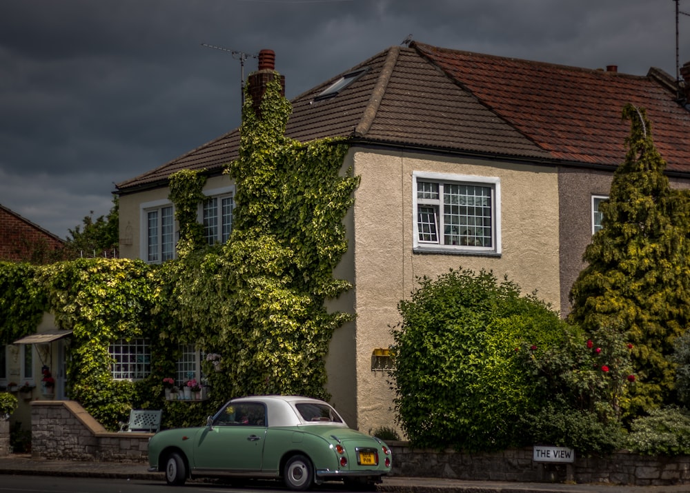 green and white coupe parked outside the house