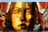 A mural painted on a brick wall, featuring the realistic portrait of a woman with long hair. The artwork uses a vibrant color palette, primarily in shades of yellow, brown, and red. The detailed shading and expression on her face create a striking visual impact. Surrounding elements include graffiti art and signatures in various colors, adding an urban feel.